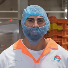 Man in hair and face net and uniform smiling